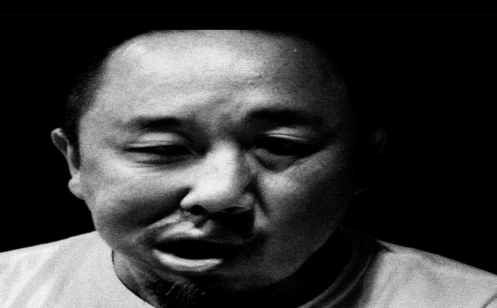 A black and white portrait of Yan Jun shaking his head