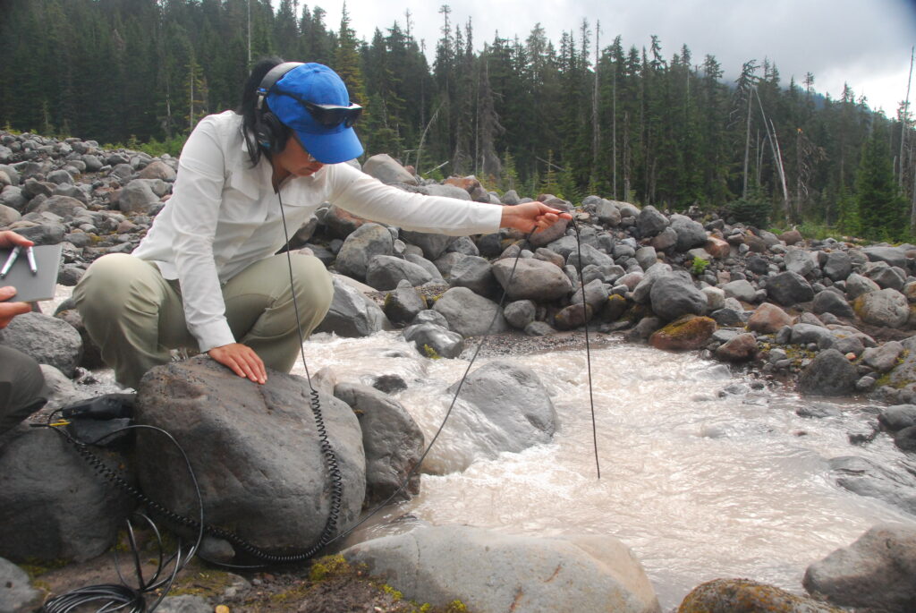 Woman in blue cap next to a fast flowing stream