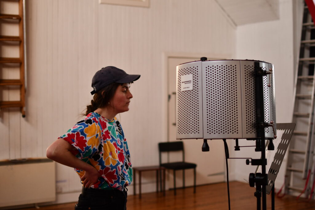 Woman with cap on standing in front of shielded microphone
