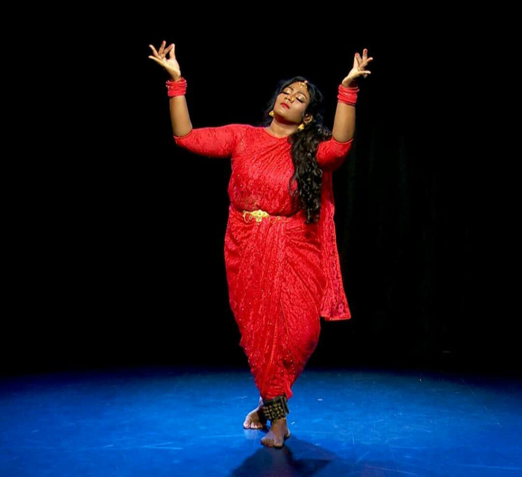 woman dancer in red dress gesturing with both hands upwards
